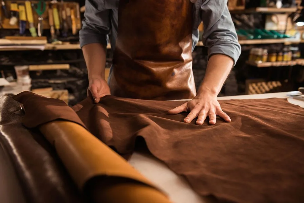 Gros plan sur les mains d'un artisan travaillant une pièce de cuir