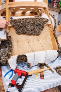 Fauteuil ancien dégarni en cours de réparation dans un atelier de tapisserie