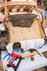 Fauteuil ancien dégarni en cours de réparation dans un atelier de tapisserie