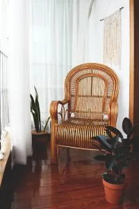 Chaise à bascule en bois avec assise et dossier cannés près d'une fenêtre