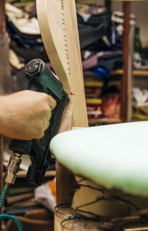 Tapissier d'ameublement en train de refaire l'assise d'une chaise à l'atelier