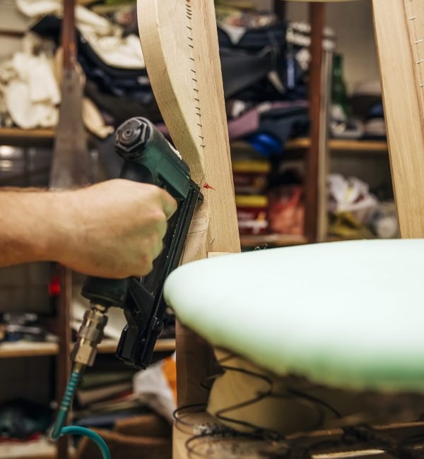 Tapissier d'ameublement en train de refaire l'assise d'une chaise à l'atelier