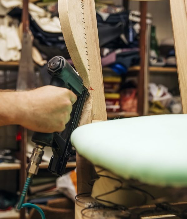 Tapissier d'ameublement en train de refaire l'assise d'une chaise à l'atelier