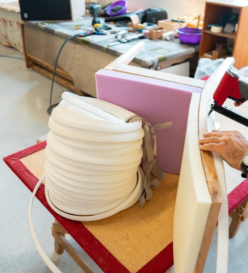 Tapissier posant la garniture d'un siège dans son atelier