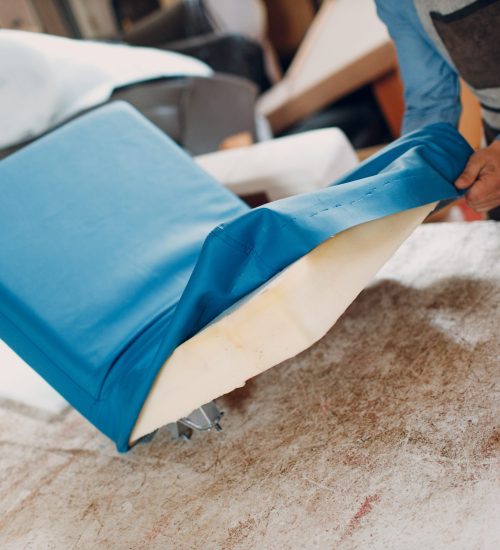 Tapissier agrafant un tissu neuf sur l'assise d'un fauteuil