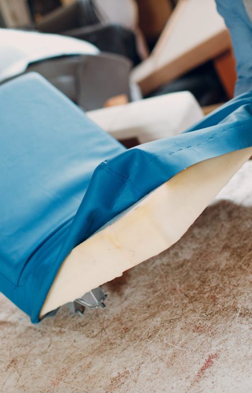 Tapissier agrafant un tissu neuf sur l'assise d'un fauteuil