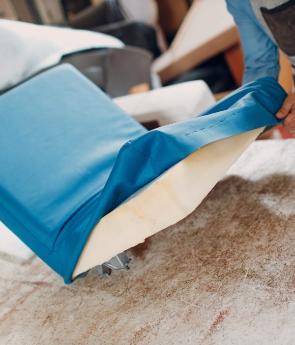 Tapissier agrafant un tissu neuf sur l'assise d'un fauteuil