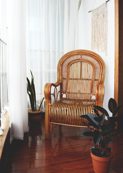 Chaise à bascule en bois avec assise et dossier cannés près d'une fenêtre