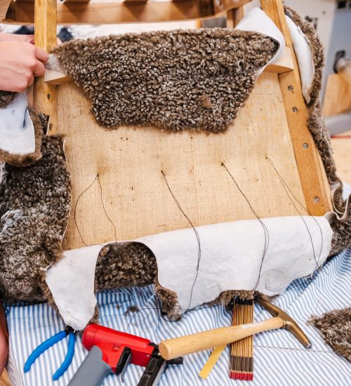 Fauteuil ancien dégarni en cours de réparation dans un atelier de tapisserie