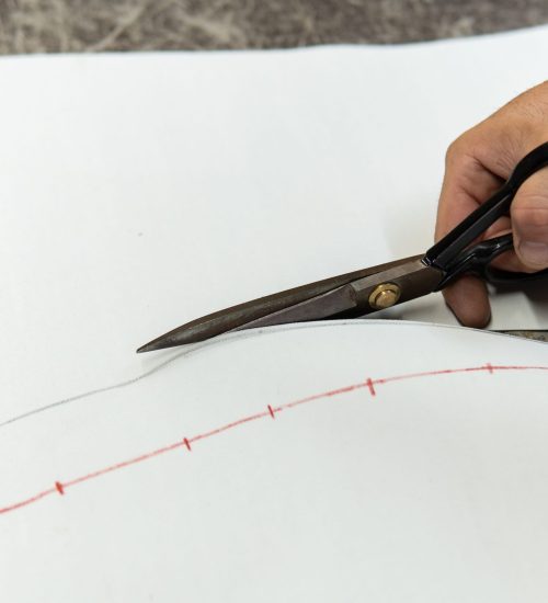 Mains d'un tapissier découpant une pièce de cuir avec des ciseaux