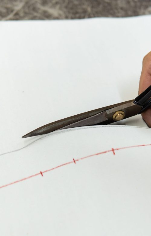 Mains d'un tapissier découpant une pièce de cuir avec des ciseaux