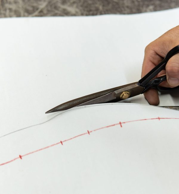 Mains d'un tapissier découpant une pièce de cuir avec des ciseaux