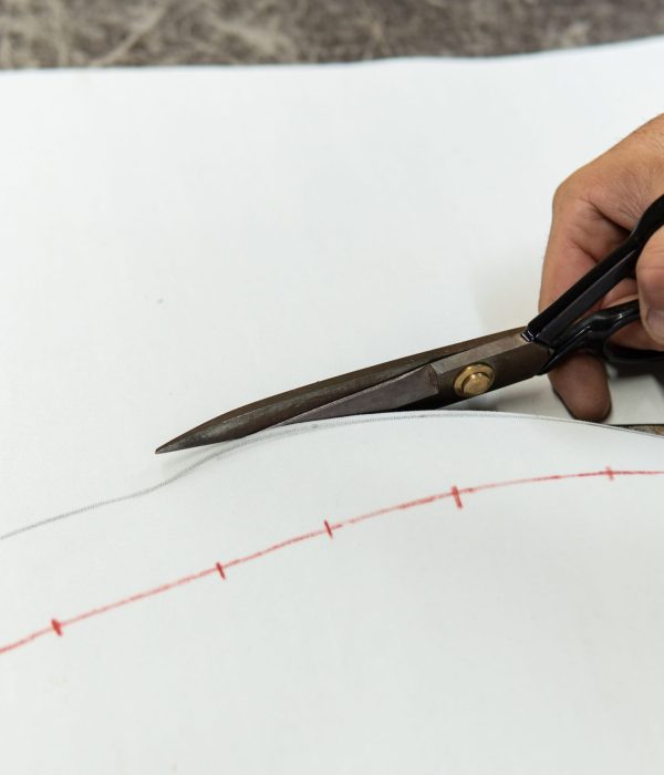 Mains d'un tapissier découpant une pièce de cuir avec des ciseaux